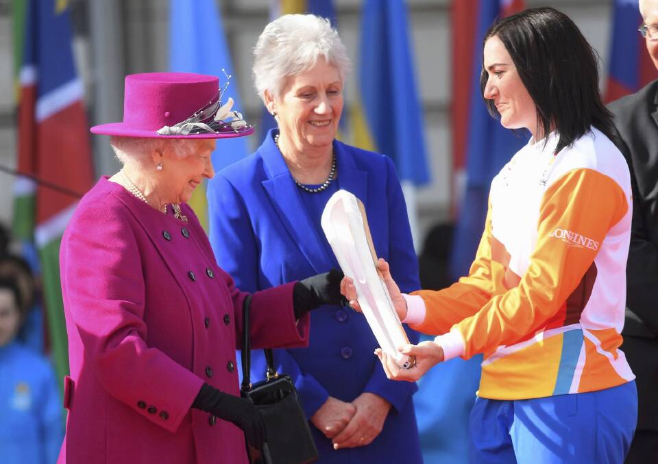 Retired Australian cyclist Anna Mears, receives the Commonwealth Games relay baton from Queen Elizabeth II at the launch of the relay at Buckingham Palace in London. Photo: Toby Melville.
