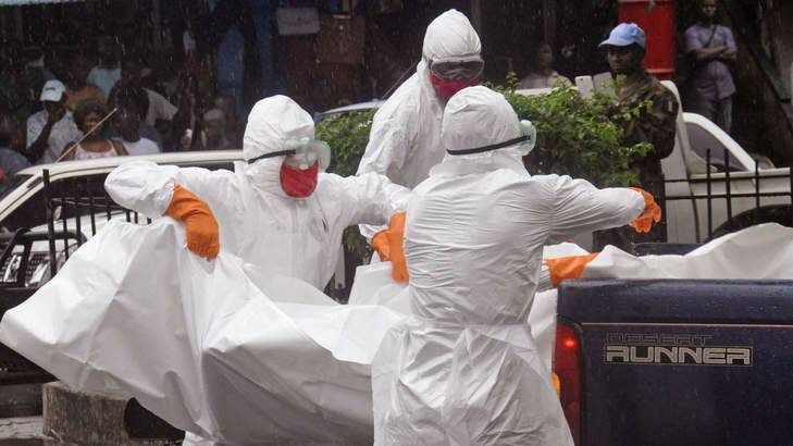 Health workers load the body of an amputee suspected of dying from the Ebola virus on the back of a truck, in a busy street in Monrovia, Liberia. Photo: AP Photo