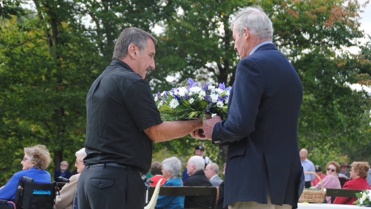 David Tuia hands the Lions Club wreath to Bruce Hearman.