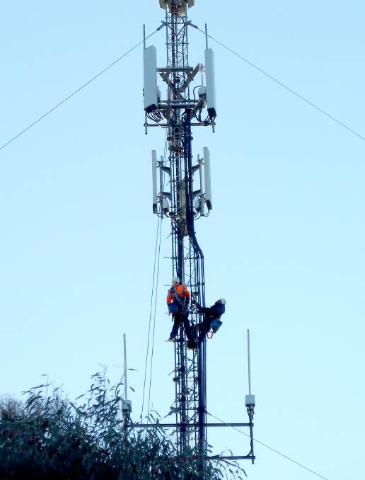 Workmen install the fitting to take the NBN Wireless receivers and transmitters. Photo: Terry Linz