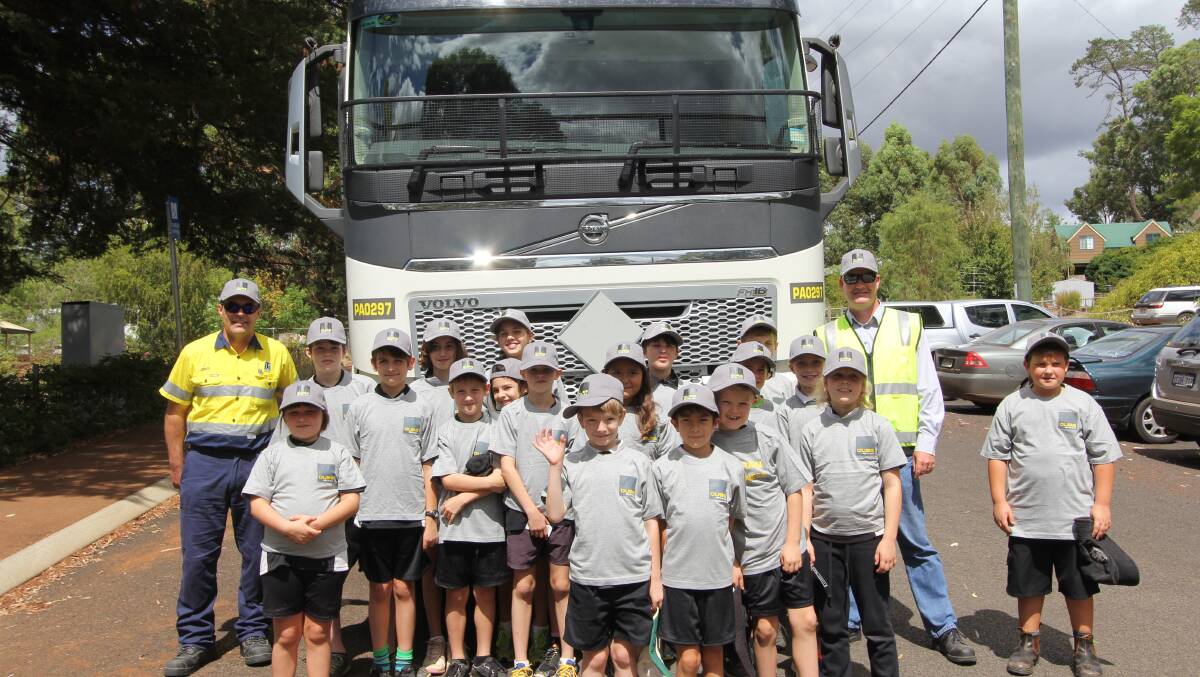 Balingup Primary School students Ben Wedderburn, Ryley Fisher, Katie Guest, Stephanie Aldridge, Yali Harris, Mason Bugg, Arki Schipp, Layla McConnell, Kailee Bugg, Brodie Fisher, Oran Kennedy, Emerald Kyaw, Kane Bennett, Samuel Wedderburn, Akira Newman, Finlay Kennedy, Aimee Robson and Rhylie Scarrott with Stewart McMurray from Qube Transport and David Hall from Talison Lithium at the Truck Safety and Awareness Seminar held at the school in March. 