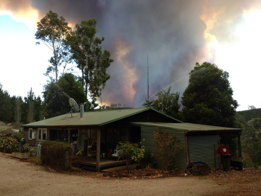 Threatening: Flames rise behind a cottage on five gate road. Picture: Tony Grey