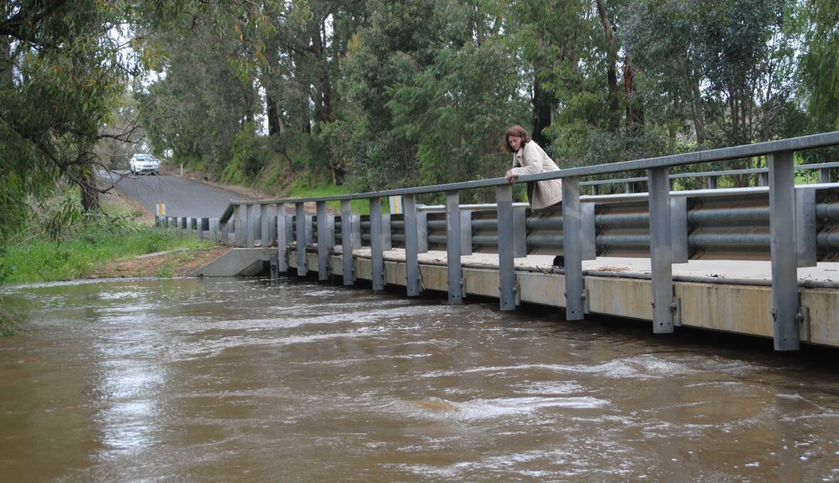 Joanne Slade watches the river come up from the Bendall Road Bridge, which was submerged in the last flood.