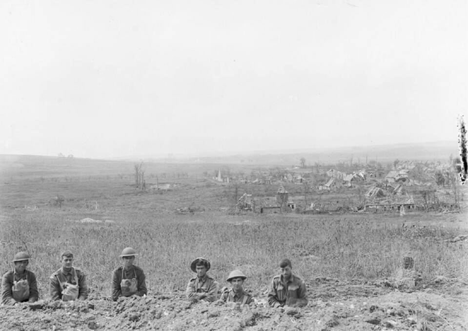 UNITED FRONT: Australian and American troops in a trench after the Battle of Hamel with the village, then freed of Germans, behind them. The entire coordinated offensive took just 93 minutes. Picture: AWM E02844